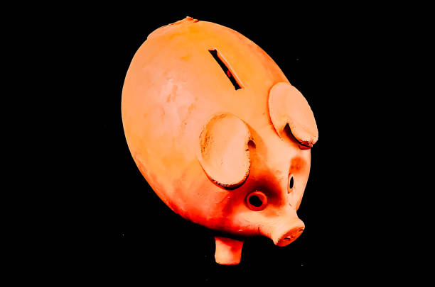A piggy bank is shown in a black background. The piggy bank is orange and has a hole in the middle
