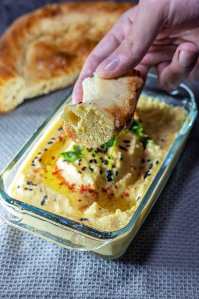 istock A man's hand holds a flatbread dipped in hummus 2192693944