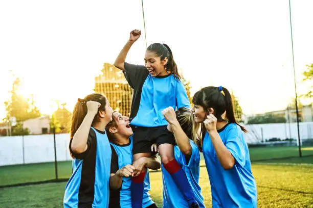 Girls soccer player carrying teammate on shoulders after win Girls soccer player carrying teammate on shoulders after win