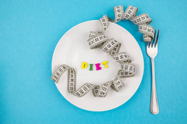 istock Creative flat lay composition with plate and measuring tape on dewy background. Intermittent fasting, ketogenic, diet concept. flat lay 2192696408