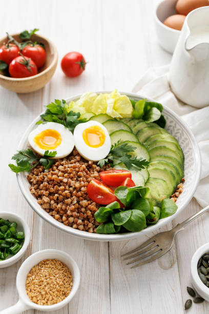 istock Buckwheat groats with avocado, various vegetables and soft-boiled egg in a ceramic bowl on a white table, close-up 2192697496