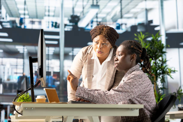 istock Young employee and manager gathered around a computer discussing objectives 2192702030