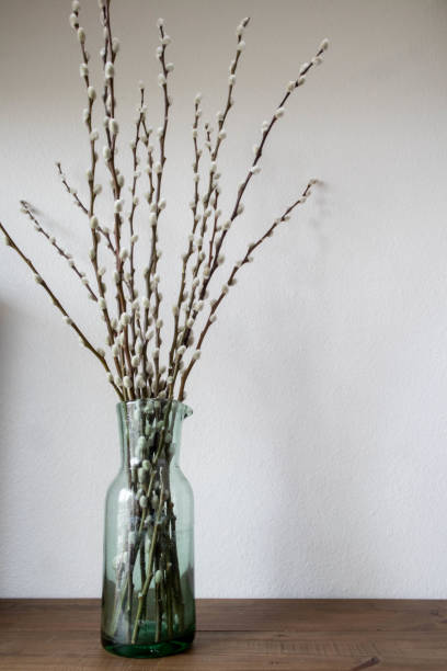 istock Graceful willow branches arranged in green glass vase on table. 2192702637