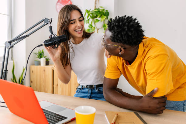 Two young millennial content creator students having fun recording radio podcast stock photo