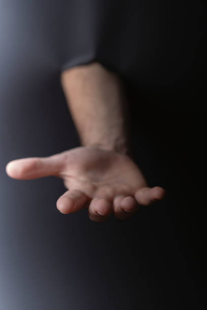 istock photo Open hand extending from dark background symbolizing gesture communication, human connection, assistance, support, or invitation for interaction and trust 2192707697