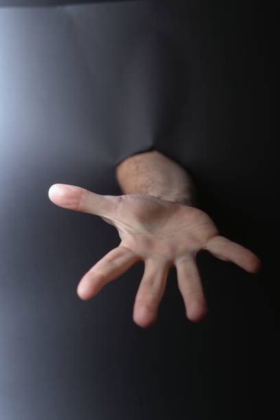 istock photo Outreach and Connection: Hand Reaching Through Dark Space Symbolizing Desire for Help, Assistance, and Generosity in Human Interaction and Emotional Outreach 2192707707