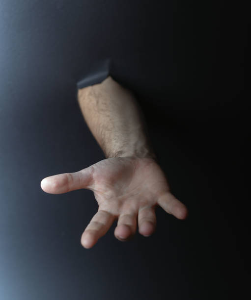 istock photo Mystical and Intriguing Conceptual Image Featuring a Human Hand Emerging Through a Dark Background, Evoking Themes of Mystery, Seeking, and Human Connection 2192707716