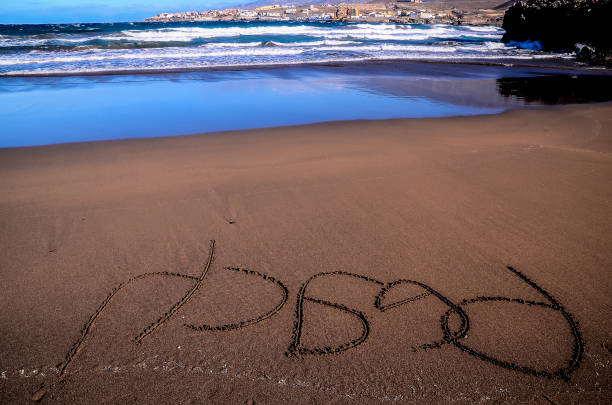 The beach is calm and peaceful. The water is blue and the sand is brown. The word \