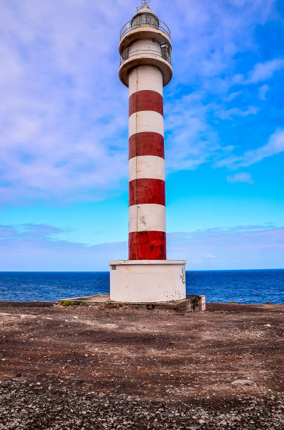 istock A lighthouse is standing on a rocky shoreline 2192712448