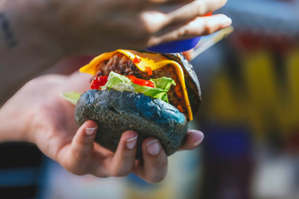 Adding Sauce to a Colorful Gourmet Cheeseburger