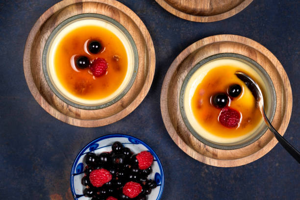 Creme Brulee a traditional french vanilla cream dessert in glass dishes with raspberry and black current on the side.