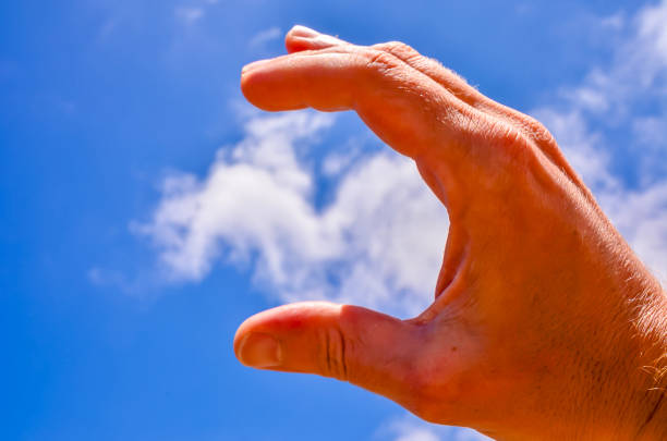A hand is shown in the air with a cloud in the background. The hand is making a \