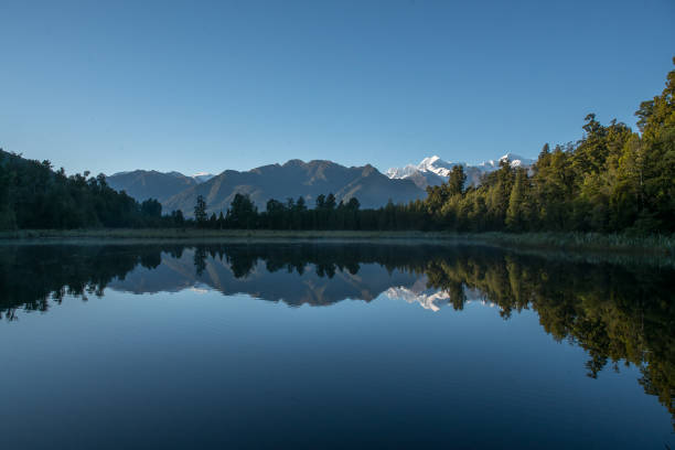 Hiking through lush native bush pedestrian footpath around the lakeside of Lake Matheson