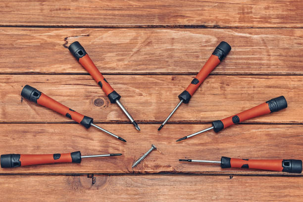 Screwdriver and screw on wooden background horizontal shot
