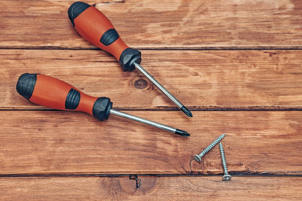 Screwdriver and screw on wooden background horizontal shot