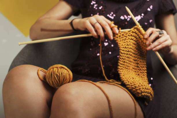 Beautiful woman in a fur sweater knitting her winter wardrobe. Winter atmosphere at home. Kitsch - shund concept.
