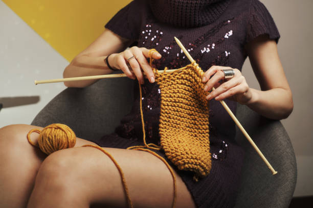 Beautiful woman in a fur sweater knitting her winter wardrobe. Winter atmosphere at home. Kitsch - shund concept.