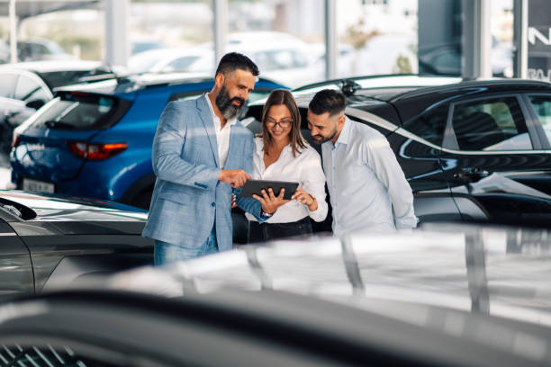 istock Car salesman showing vehicles to a couple using a digital tablet 2192729520