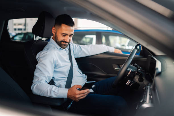 istock Happy businessman using smartphone inside new car at dealership 2192729548