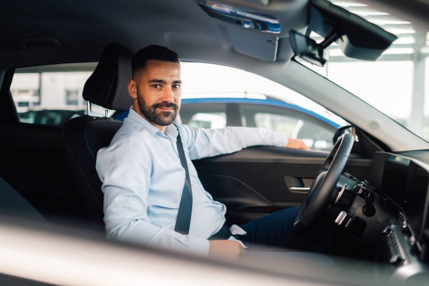 istock Salesman sitting in new car and looking at camera 2192729555