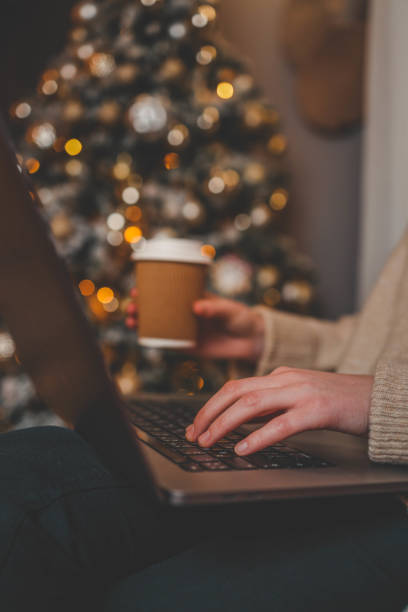 istock Hands typing on a laptop with a beautifully glowing Christmas tree in the background, creating a cozy and festive atmosphere indoors 2192737338