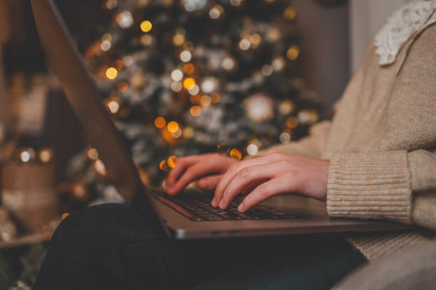 istock Hands typing on a laptop with a beautifully glowing Christmas tree in the background, creating a cozy and festive atmosphere indoors 2192737343