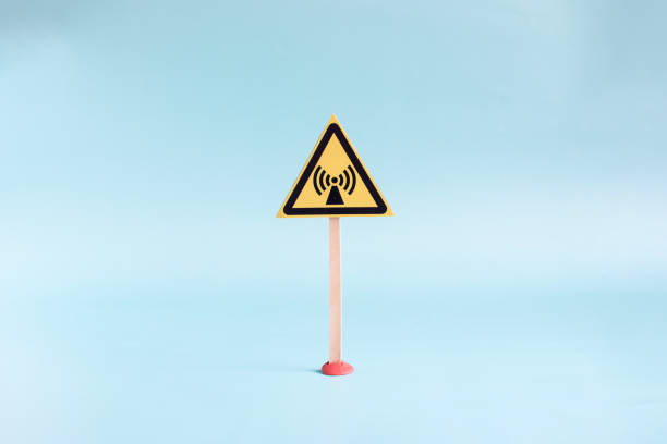 The warning sign is a yellow triangle indicating an electromagnetic field on a light background in close-up