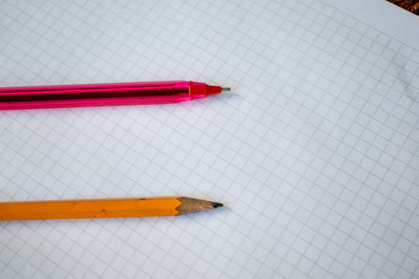 A pencil and red pen placed on a white grid paper sheet, symbolizing creativity, writing, and organization. This simple and versatile image is perfect for projects related to education, stationery, office supplies, and design. Ideal for use in advertisements, academic materials, and planning concepts