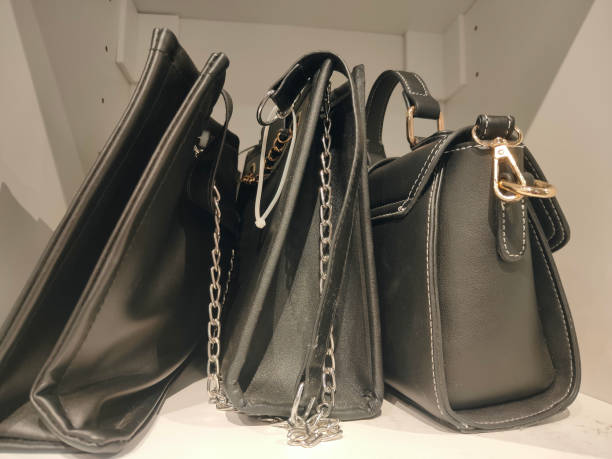 istock Three black handbags with chains and shoulder straps are on display in the store, against a white background 2192752797