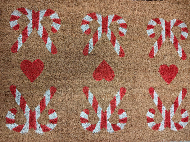 istock Hand-painted, light brown doormat with a white and red candy cane pattern, surrounded by hearts 2192753718