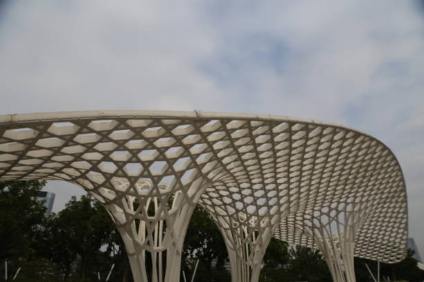 A large, white structure with a lot of intricate designs and patterns. The structure is surrounded by trees and he is a part of a park or public space. Scene is one of elegance and sophistication