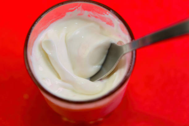 istock Creamy Yogurt with Spoon Against Red Background 2192758668