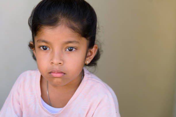 istock Young girl with a thoughtful expression sitting against a neutral backdrop in daylight 2192758837