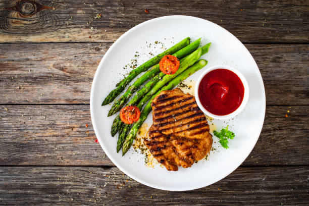 Barbecued meat and asparagus on wooden table