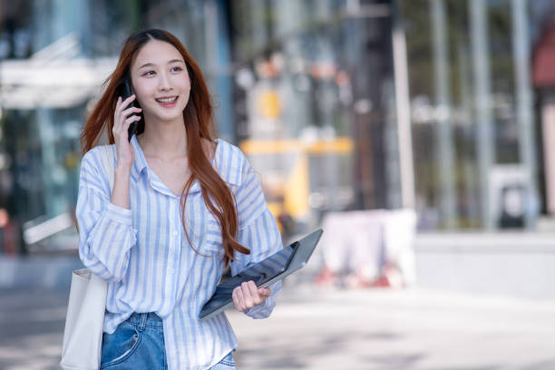istock Woman is talking on her cell phone while holding a tablet 2192761592