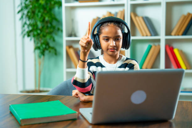 Indian Schoolgirl Attending Online Class at Home Using Computer  Learning and Technology Concept Studious Indian Asian Elementary Grade Girl Attending Virtual Online Class at Home Using Computer, Learning and Communicating with Teacher, Highlighting Modern Education, E-Learning, and Technology online tuition  stock pictures, royalty-free photos & images