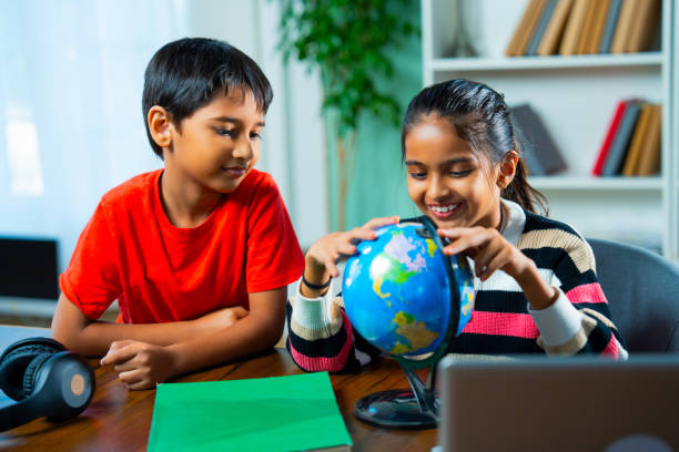 istock Indian siblings playing with an educational globe at home, discovering countries in a playful way 2192763763