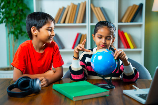 istock Indian siblings playing with an educational globe at home, discovering countries in a playful way 2192763766
