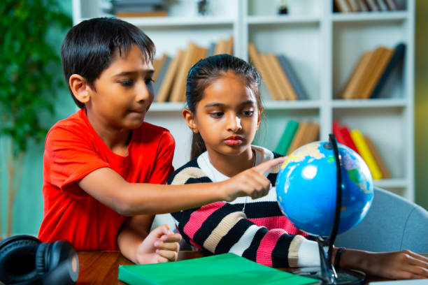 istock Indian siblings playing with an educational globe at home, discovering countries in a playful way 2192763775