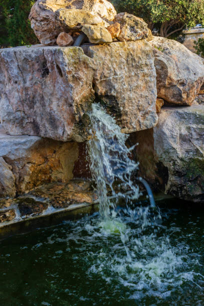 istock Small Waterfall Flowing Over Natural Stones into a Pond 2192768843