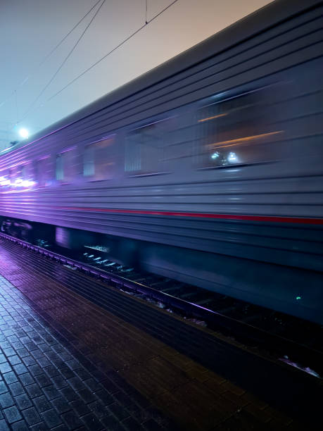 A train is moving down the tracks with purple lights on the side. The train is moving quickly and the lights are bright