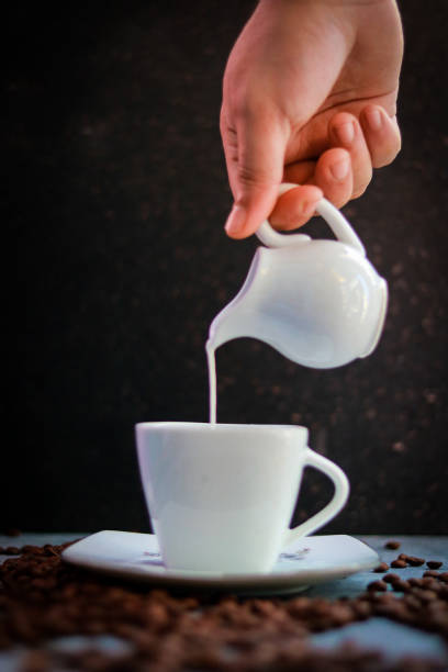 istock Pouring milk into a cup with coffee beans. Selective focus. 2192774228