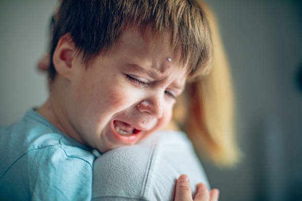 Little boy with chickenpox crying on his mothers shoulder
