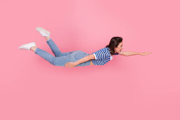 istock Playful young woman mimics flying against a vibrant pink backdrop with joyful expression and fun casual fashion 2192781128