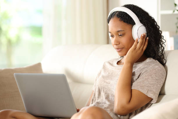 istock Black woman listening audio using laptop on a couch 2192781202