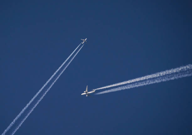 Two airplanes with vapor trails meeting up in the blue sky
