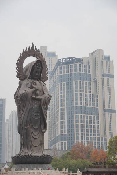 A large statue of a deity with modern skyscrapers in the background, blending tradition and urban development.