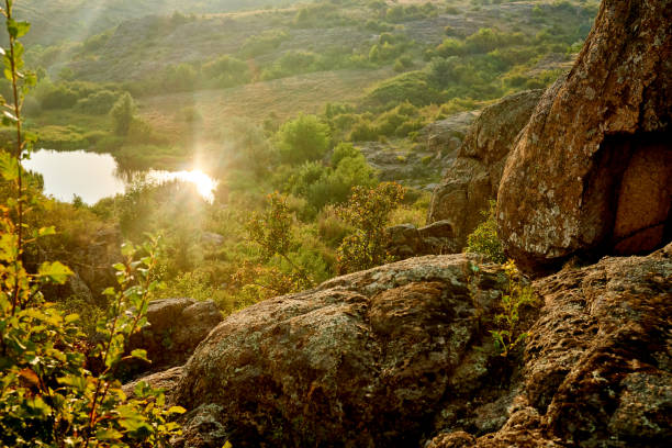 Small lake with sun rays reflection in green valley