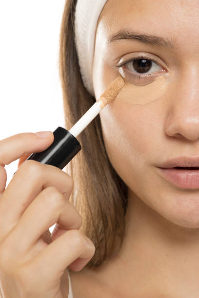 istock Beauty. Young woman applying cconcealer under her eyes on a white background. Half face. 2192787093