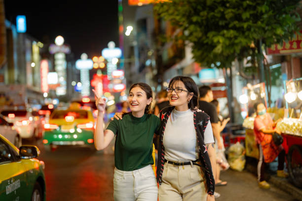 LGBTQIA couple explore street food while walking through the vibrant streets of Yaowarat Road at Night.